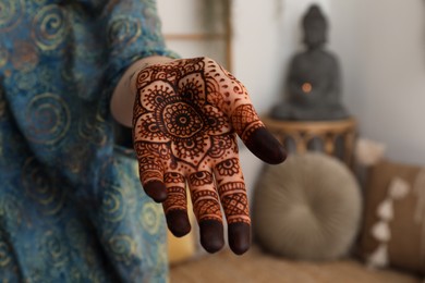 Photo of Woman with henna tattoo on palm indoors, closeup. Traditional mehndi ornament