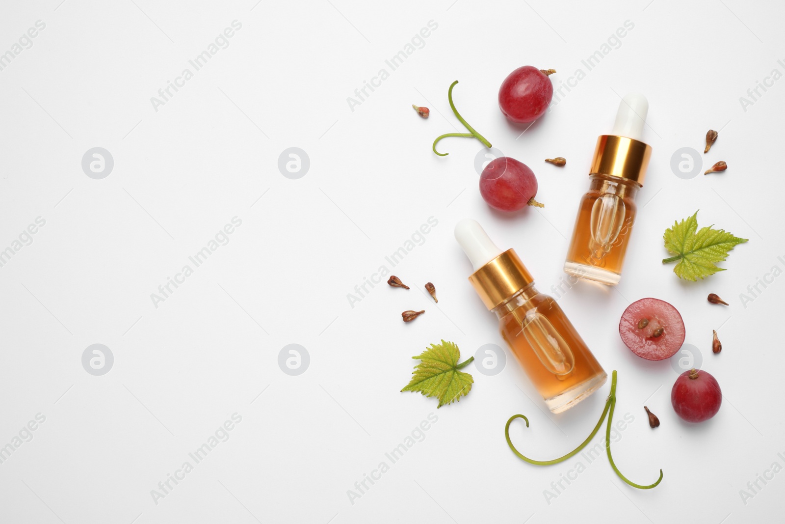 Photo of Flat lay composition with natural grape seed essential oil on white background, space for text. Organic cosmetics