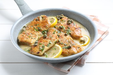 Photo of Delicious chicken piccata on white wooden table, closeup