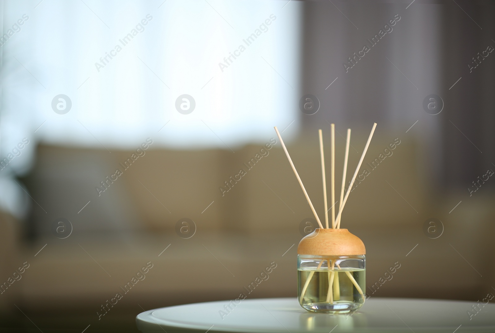 Photo of Aromatic reed air freshener on table indoors. Space for text