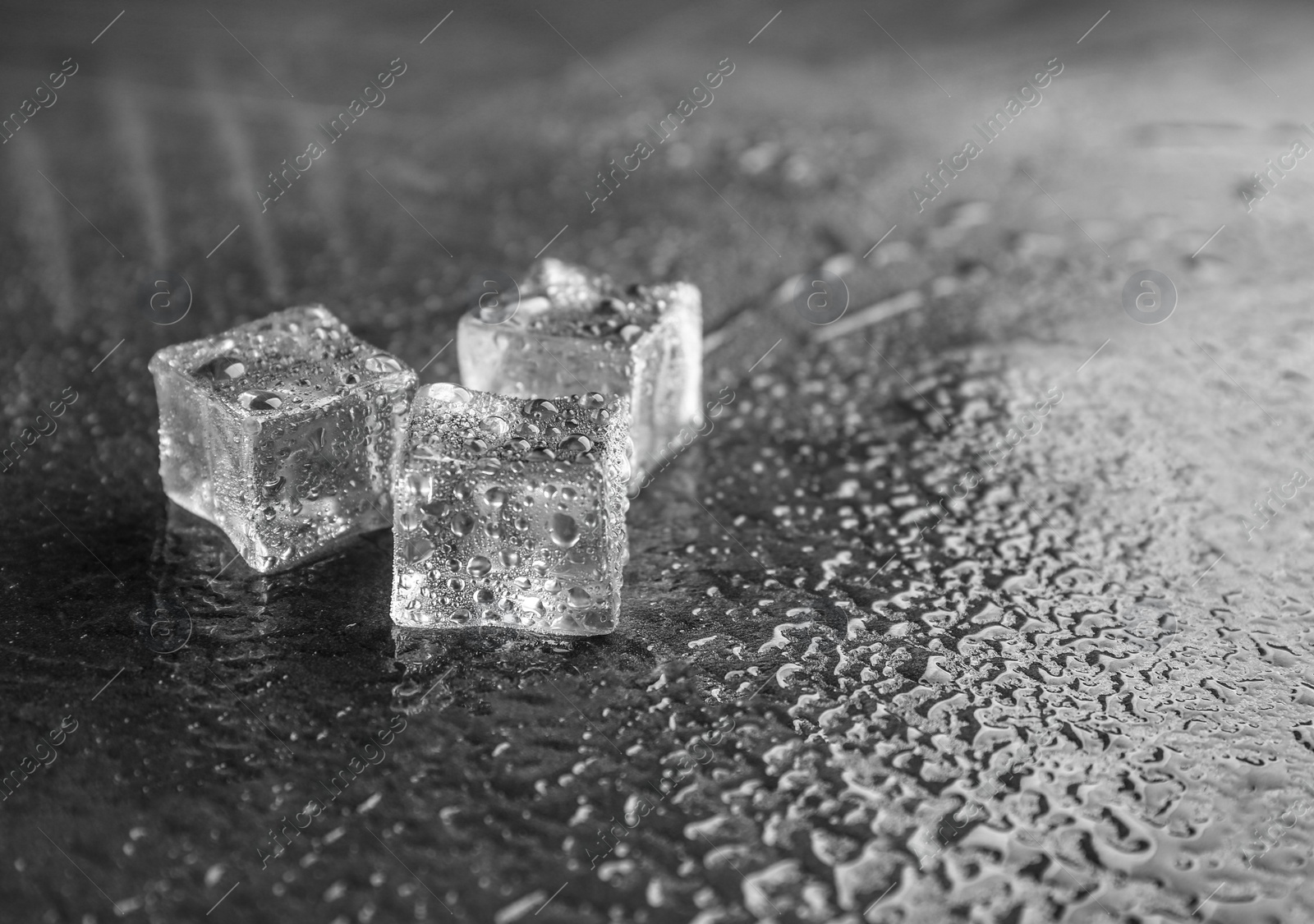 Photo of Crystal clear ice cubes on grey stone table. Space for text