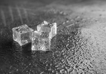 Photo of Crystal clear ice cubes on grey stone table. Space for text