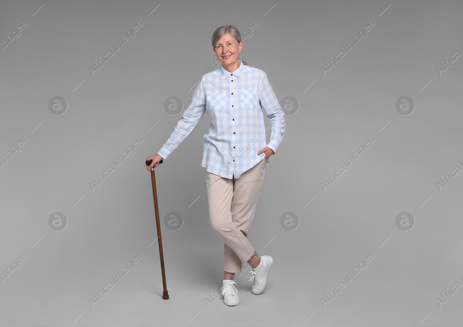 Photo of Senior woman with walking cane on gray background