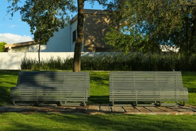 Stylish benches in green park on sunny day