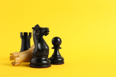 Photo of Different chess pieces on yellow background. Space for text