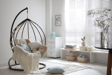 Photo of Cozy hanging chair with fairy lights in modern living room. Interior design