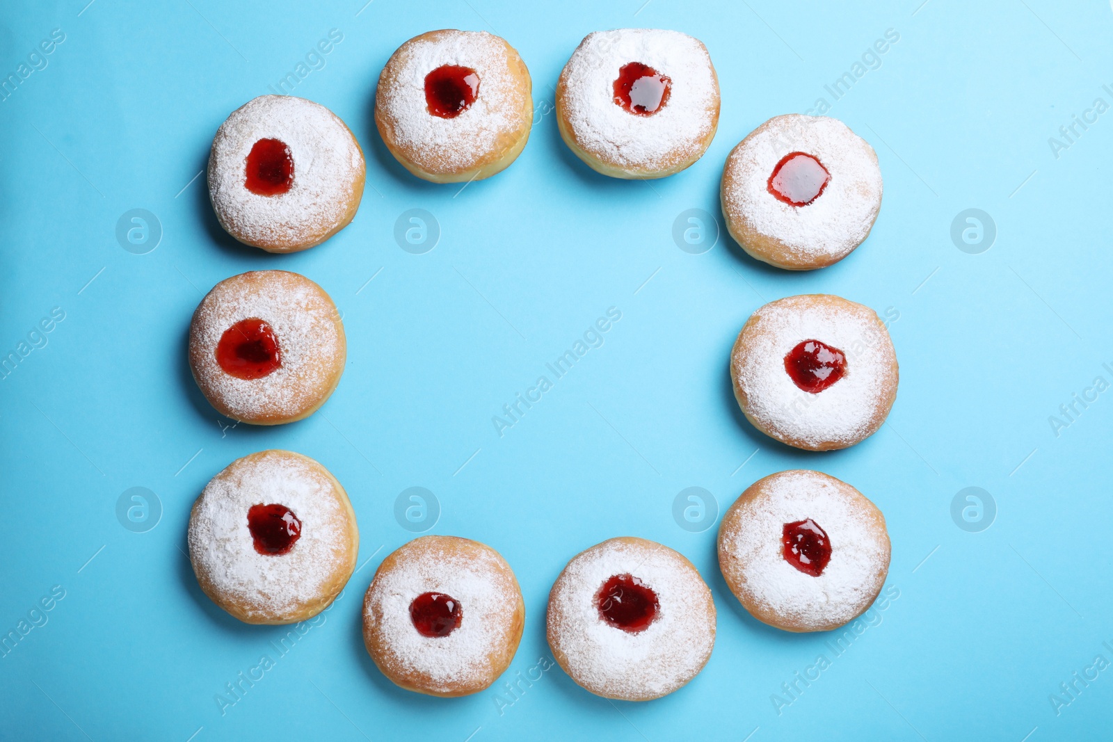 Photo of Hanukkah doughnuts with jelly and sugar powder 
on blue background, flat lay. Space for text