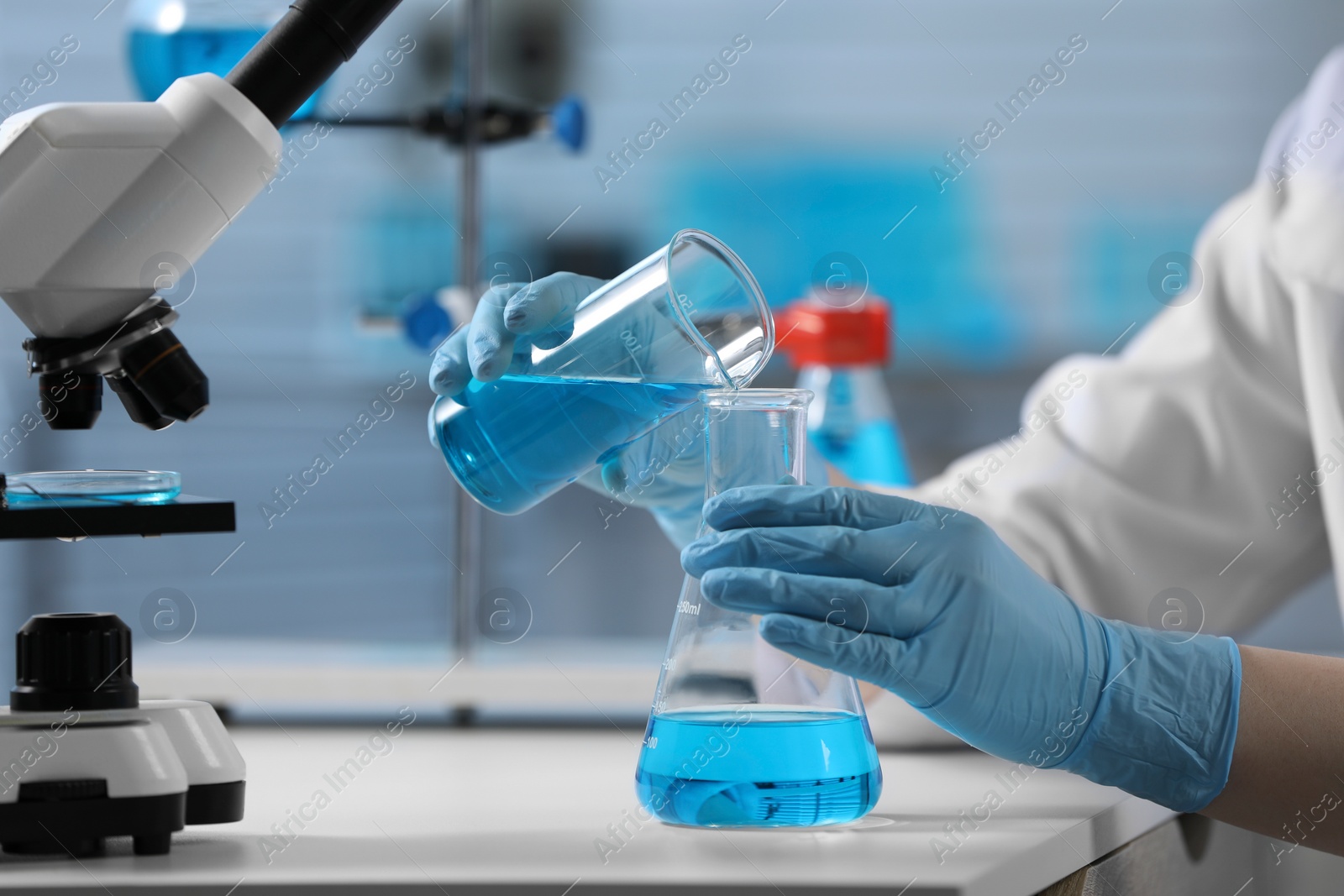 Photo of Scientist pouring sample into flask in laboratory, closeup