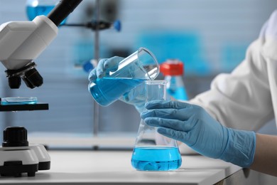 Scientist pouring sample into flask in laboratory, closeup