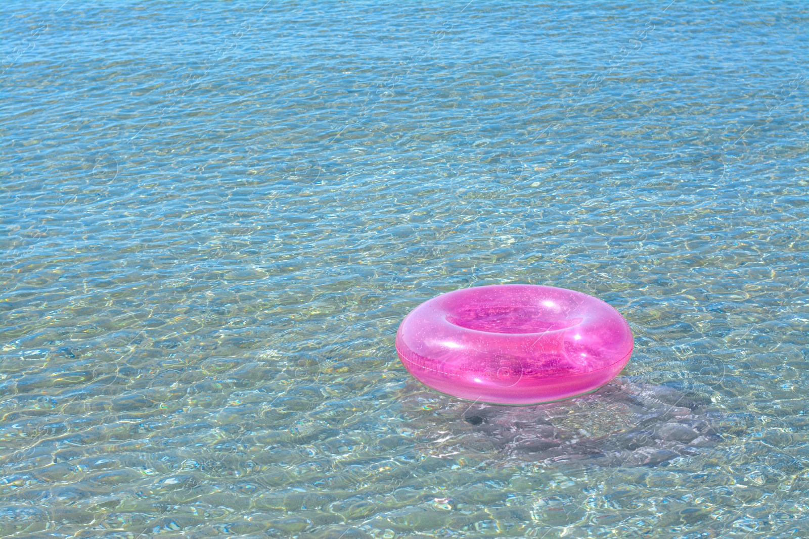 Photo of Bright inflatable ring floating on sea water. Space for text