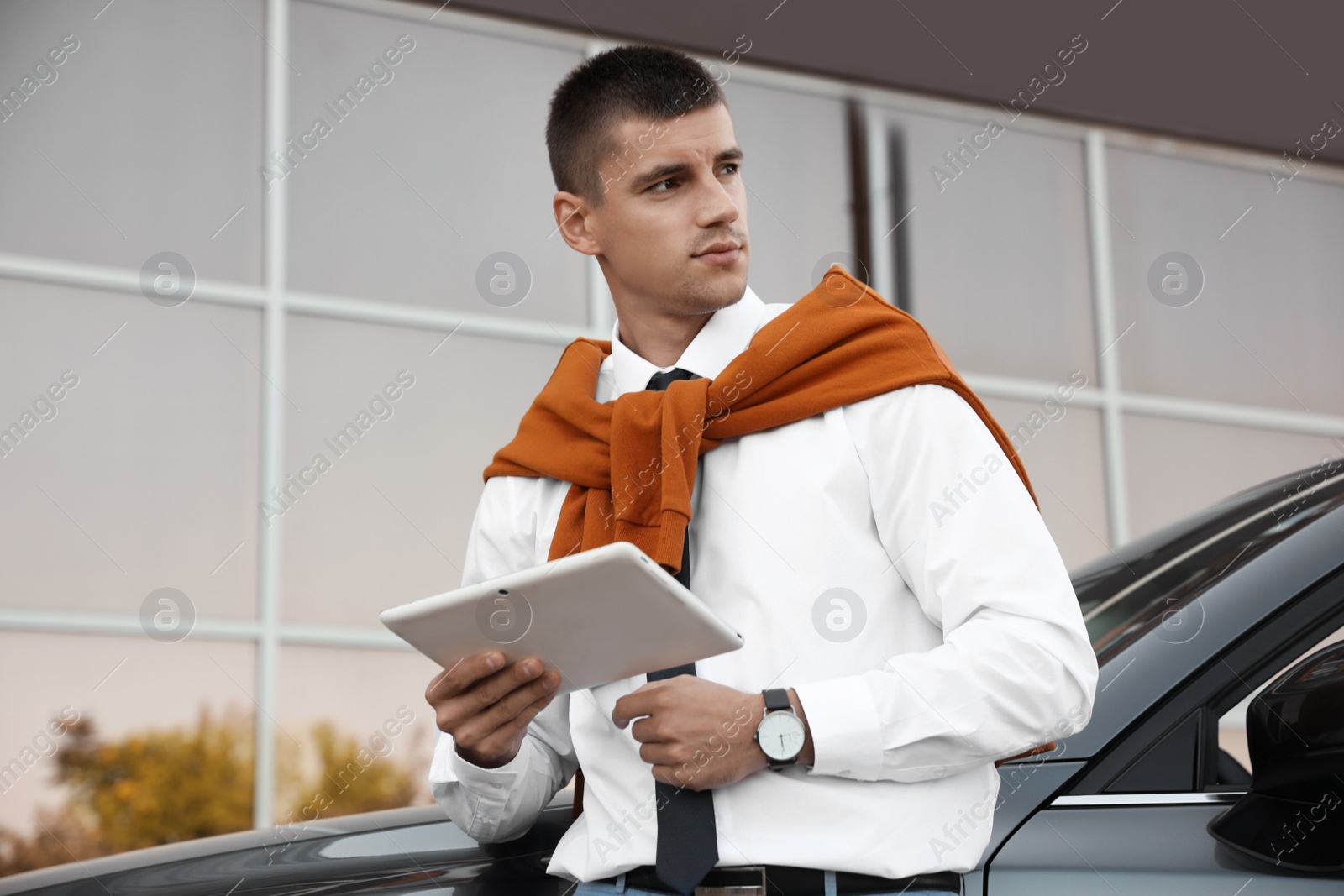 Photo of Attractive young man with tablet near luxury car outdoors