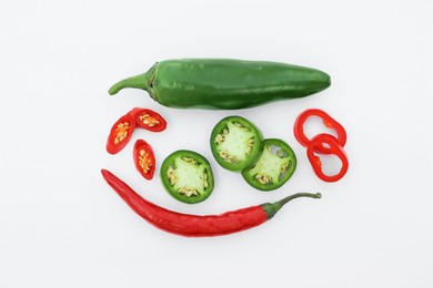 Photo of Whole and cut hot chili peppers on white background, flat lay
