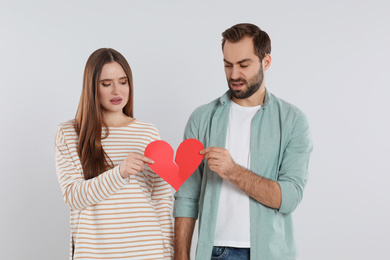 Photo of Couple tearing paper heart on light  background. Relationship problems