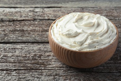 Photo of Bowl of tasty cream cheese on wooden table, space for text