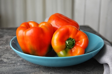 Photo of Plate with ripe paprika peppers on table