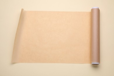 Roll of baking paper on beige background, top view