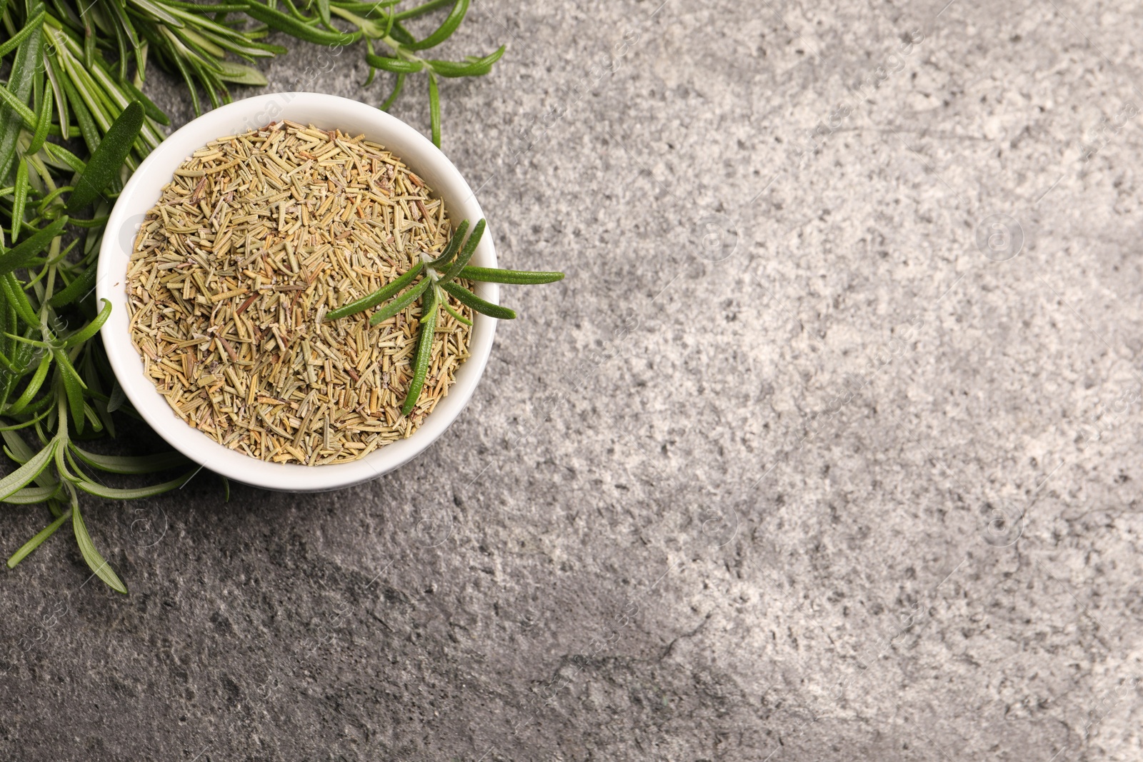 Photo of Fresh and dry rosemary on stone table, flat lay. Space for text