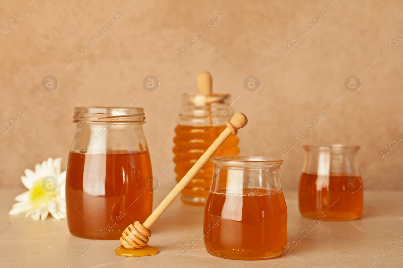 Photo of Glassware with tasty honey and dipper on table