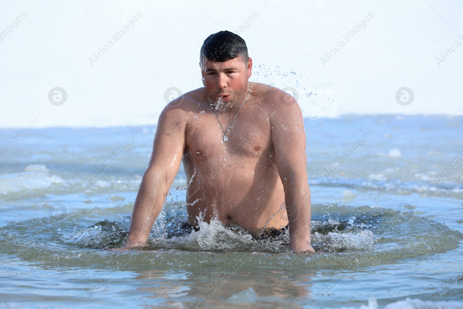 Photo of MYKOLAIV, UKRAINE - JANUARY 19, 2021: Man immersing in icy water on winter day. Traditional Baptism ritual