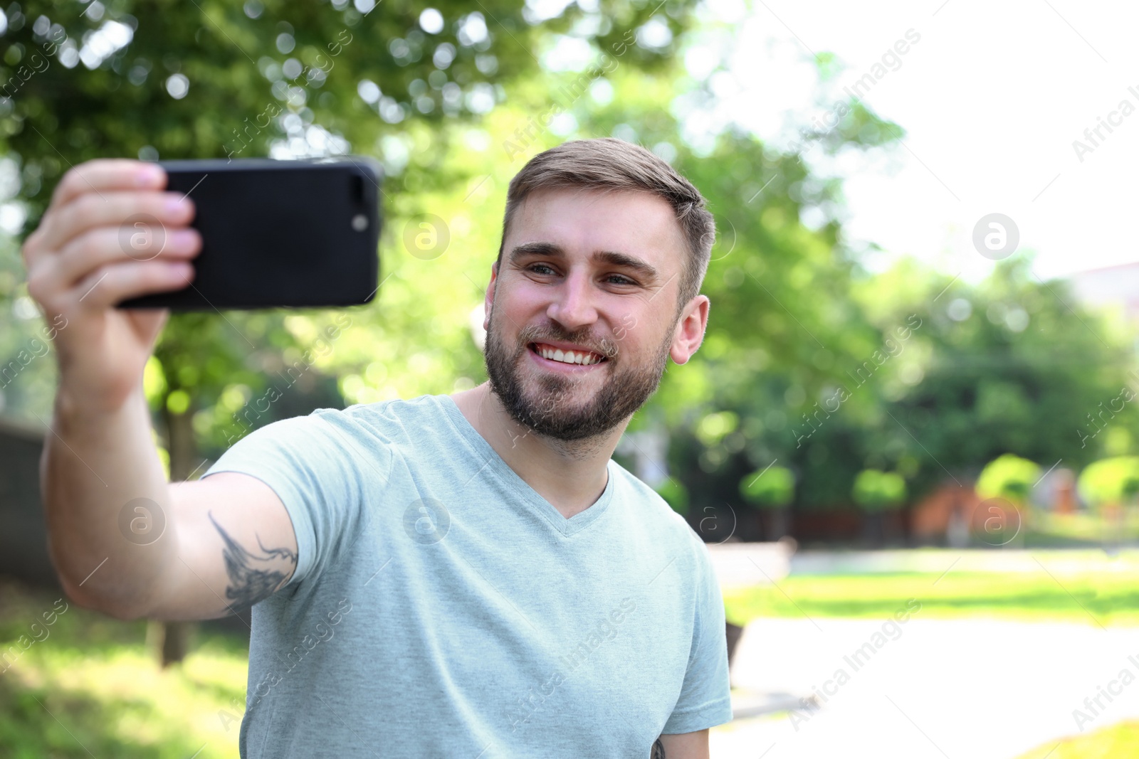 Photo of Happy young man taking selfie in park