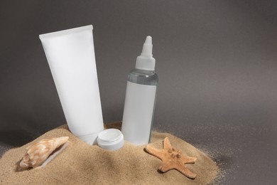 Photo of Cosmetic products, starfish and seashell on sand against grey background. Space for text