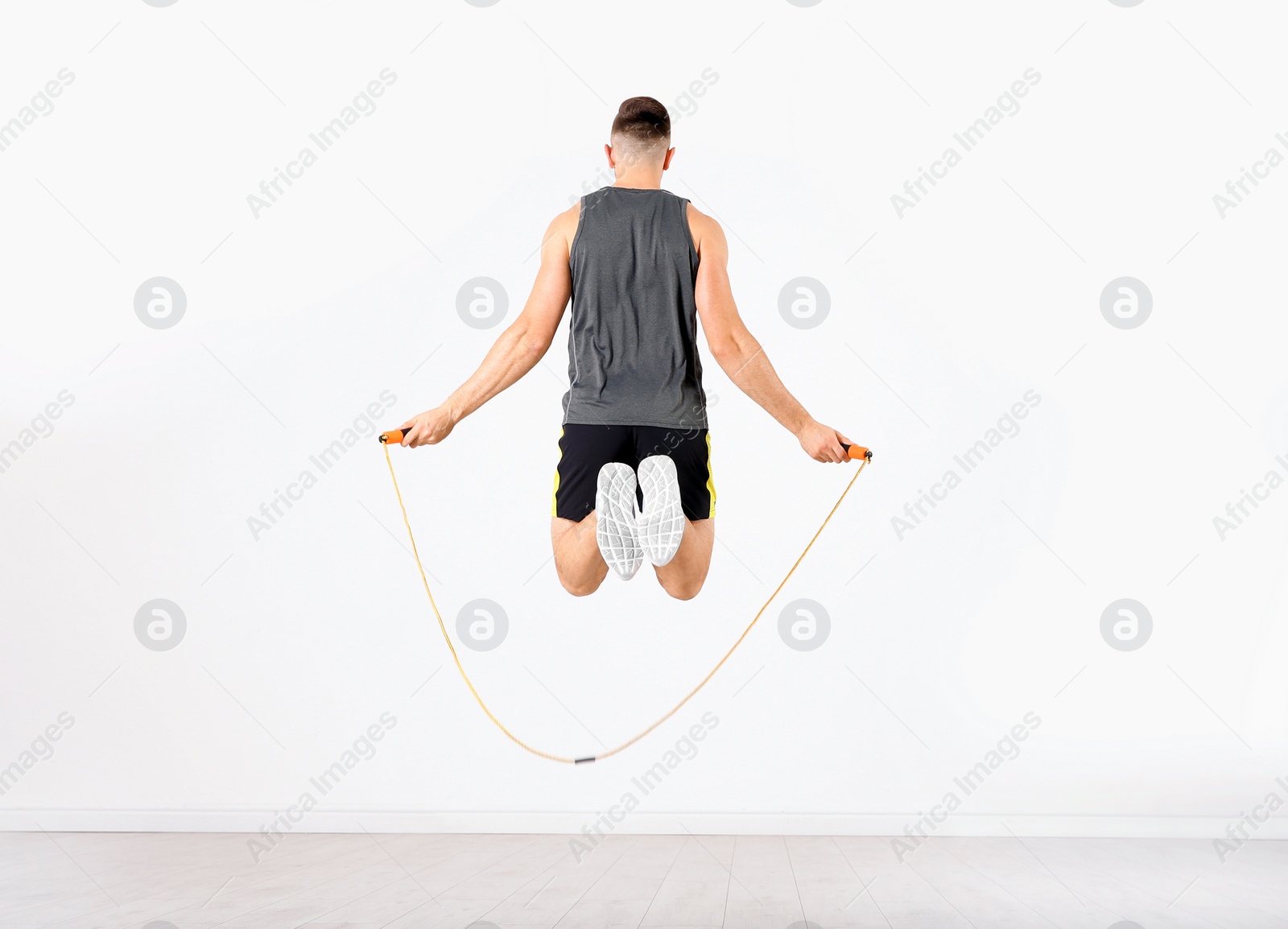 Photo of Sportive man training with jump rope in light room