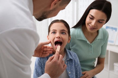 Mother with daughter visiting pediatrician in hospital. Doctor examining little girl