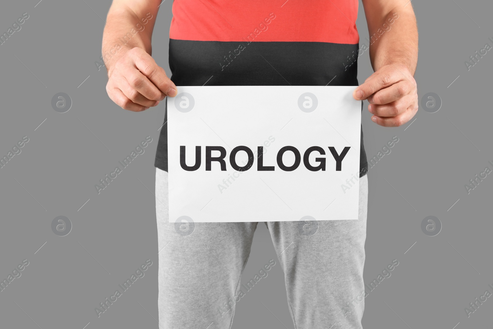 Photo of Mature man holding paper with word UROLOGY on grey background