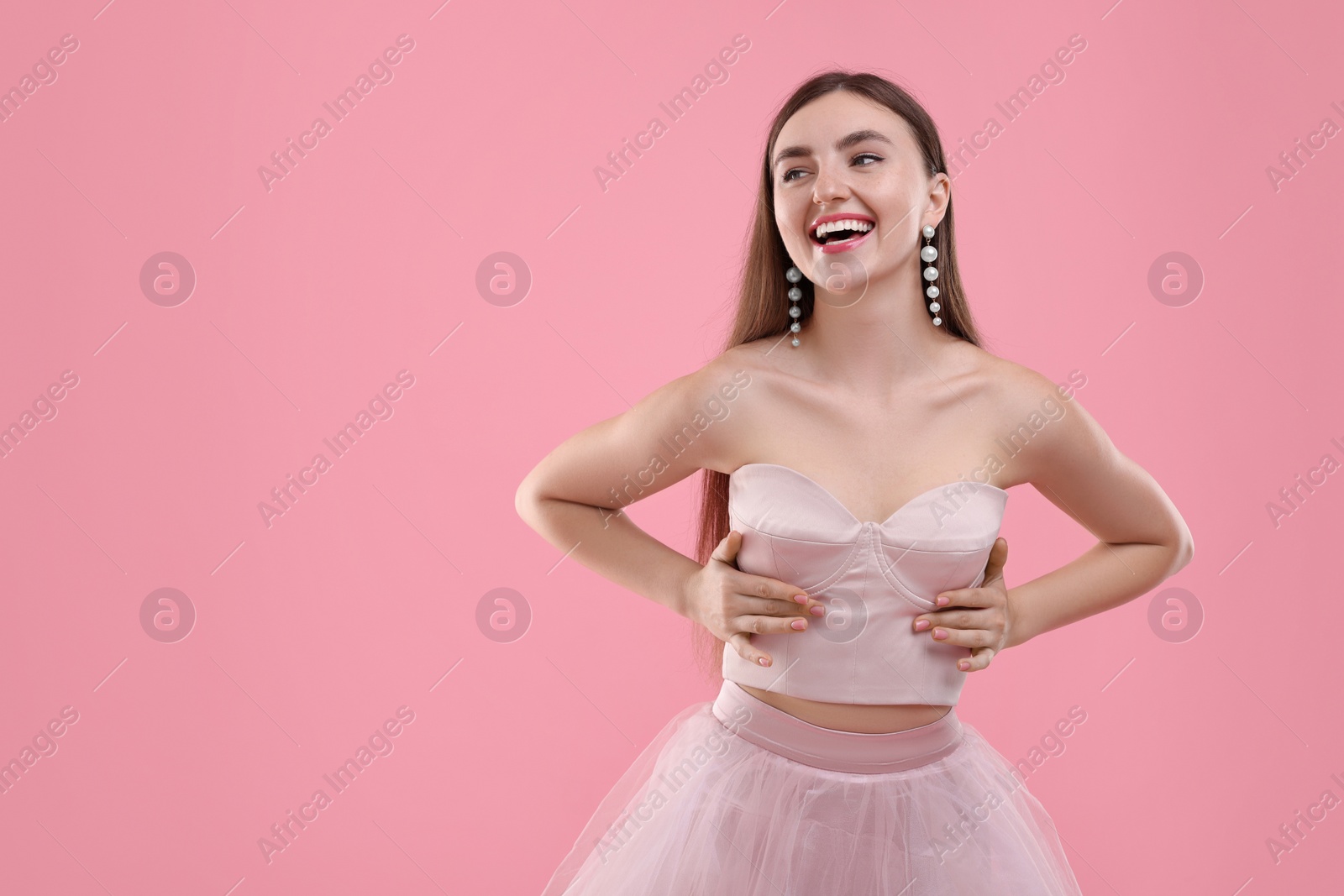 Photo of Beautiful woman in pale pink clothes on color background, space for text