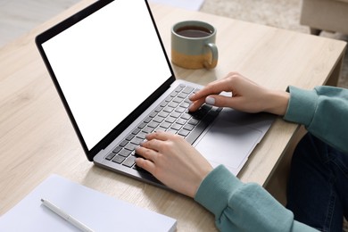 Photo of Woman working with laptop at wooden desk, closeup