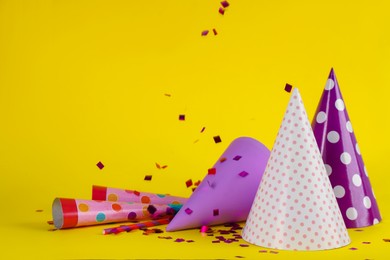 Photo of Colorful party hats and other festive items on yellow background. Space for text