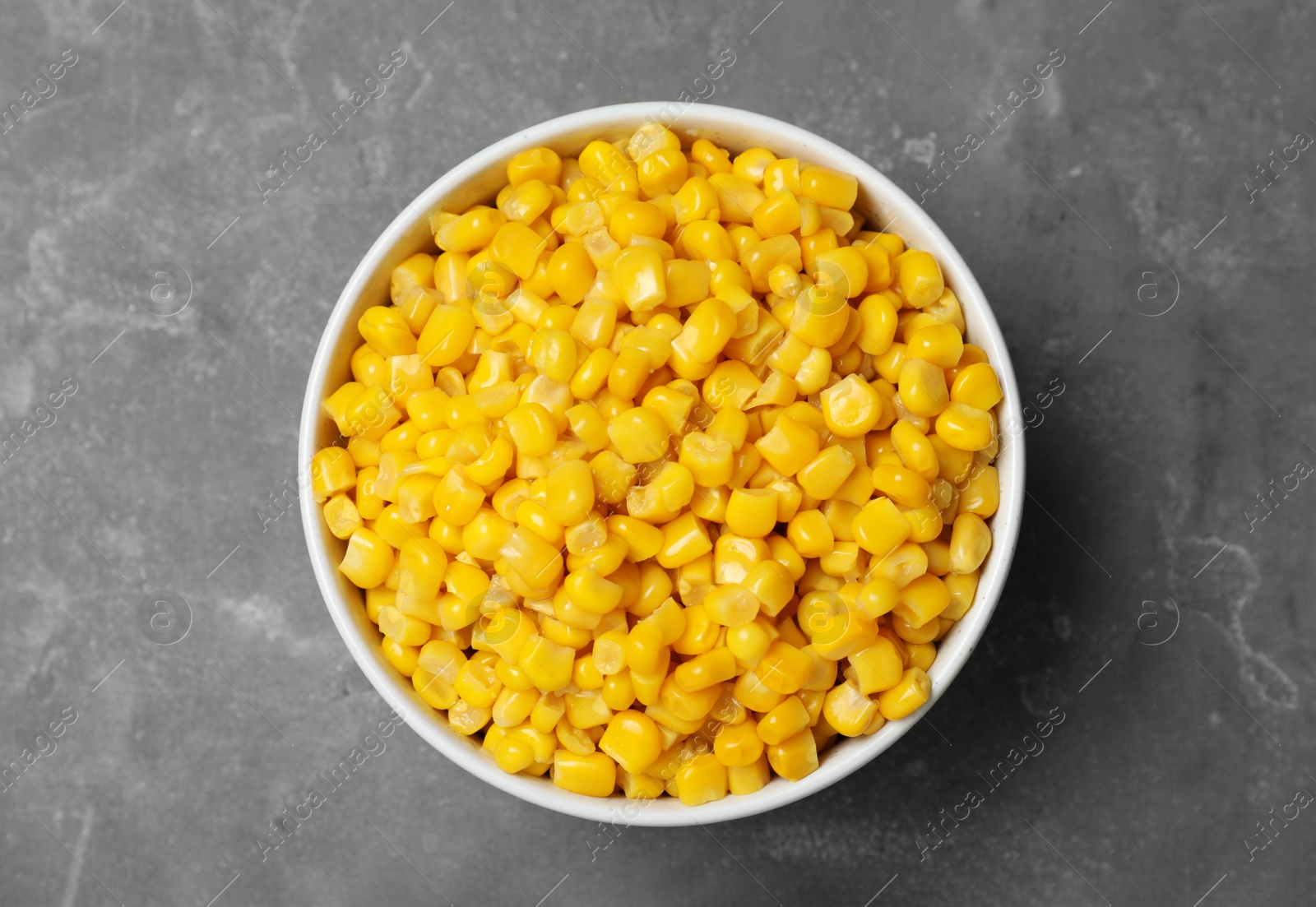 Photo of Delicious canned corn in bowl on grey table, top view