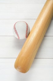 Photo of Baseball bat and ball on white wooden table, above view. Sports equipment