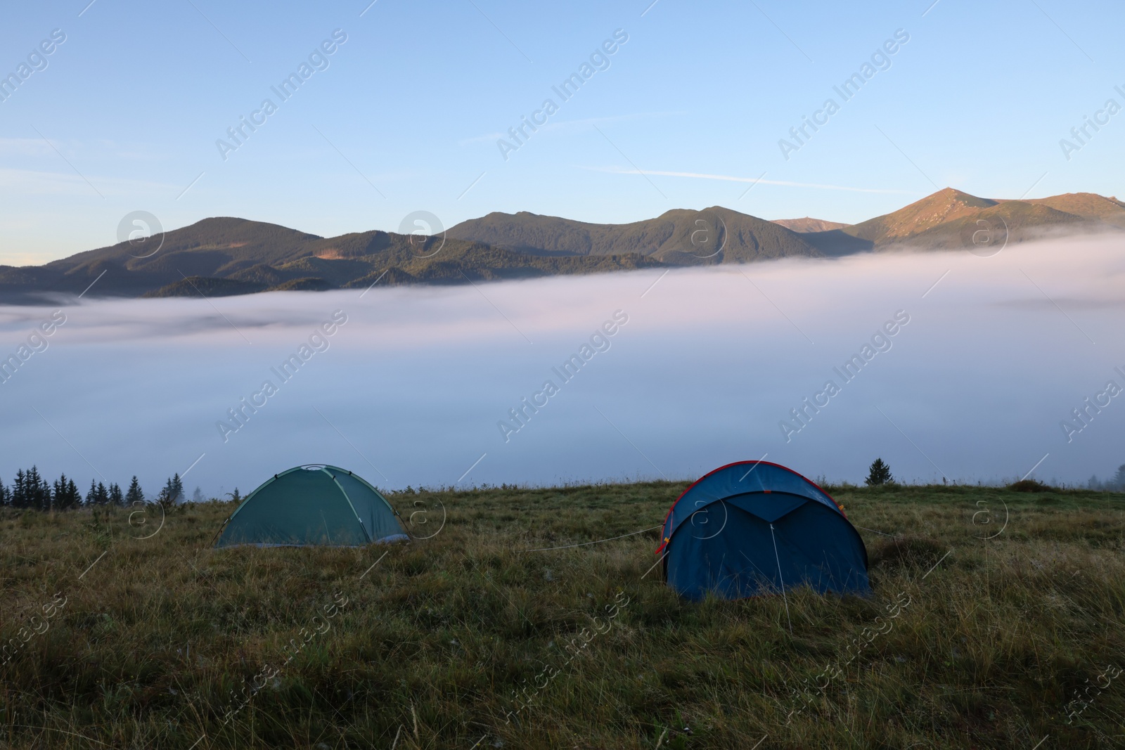 Photo of Picturesque mountain landscape with camping tents in foggy morning