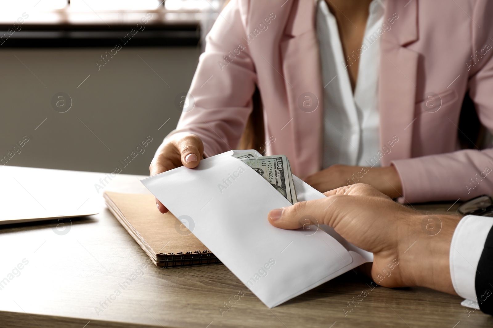 Photo of Man giving bribe to woman at table, closeup