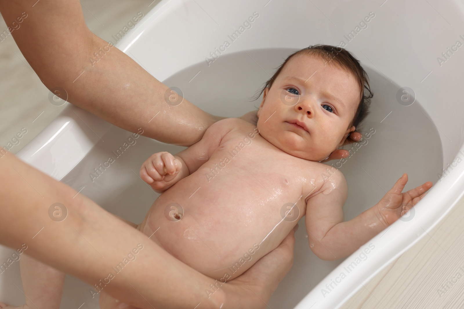 Photo of Mother bathing her little baby in bathtub, closeup