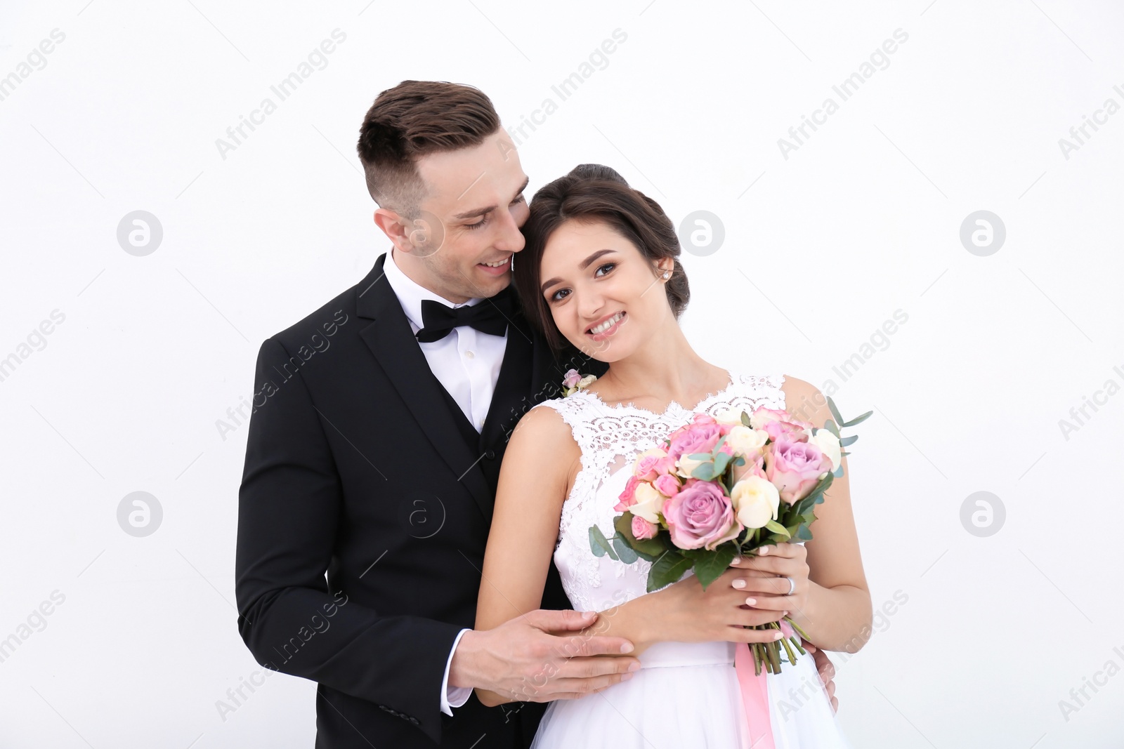 Photo of Young handsome groom and beautiful bride with bouquet on white background