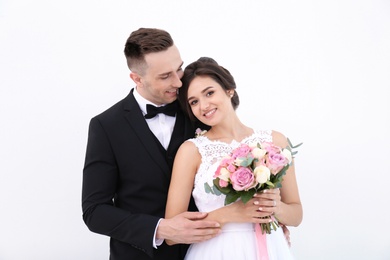 Photo of Young handsome groom and beautiful bride with bouquet on white background