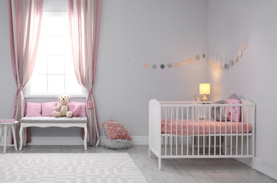 Photo of Baby room interior with comfortable crib and indoor bench