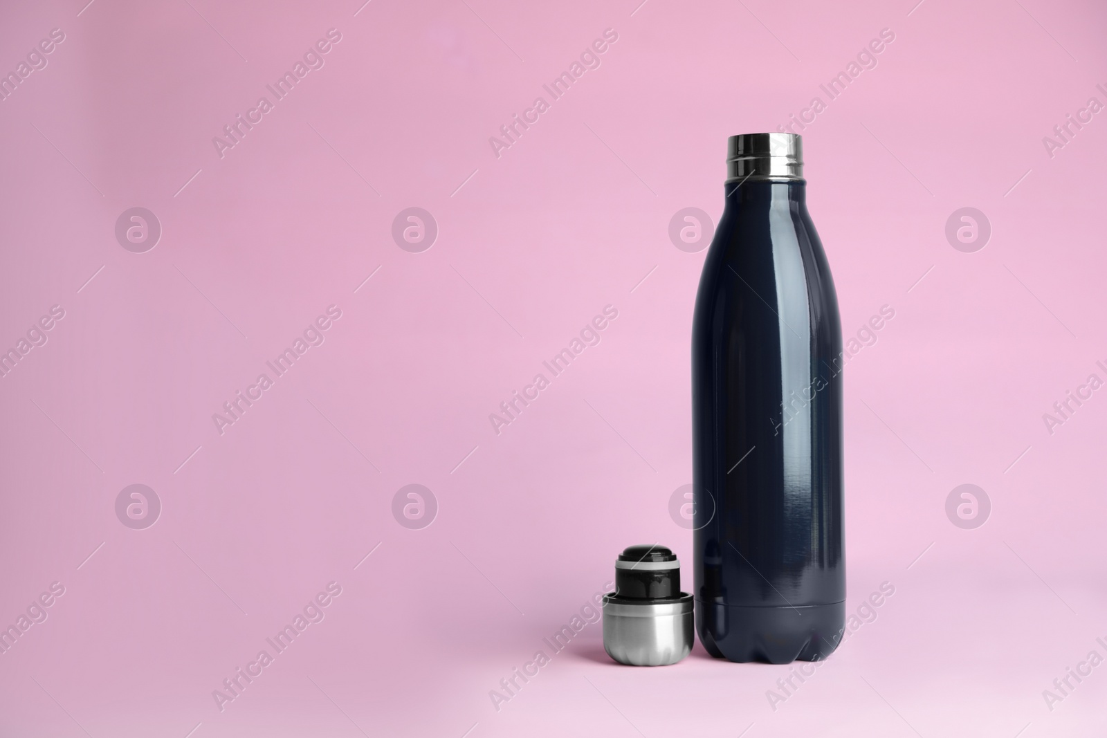 Photo of Stylish thermo bottle on pink background, space for text