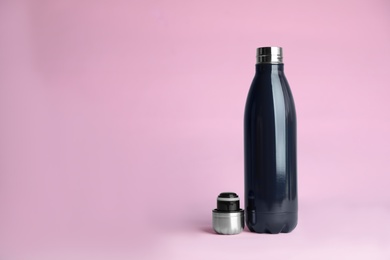 Photo of Stylish thermo bottle on pink background, space for text