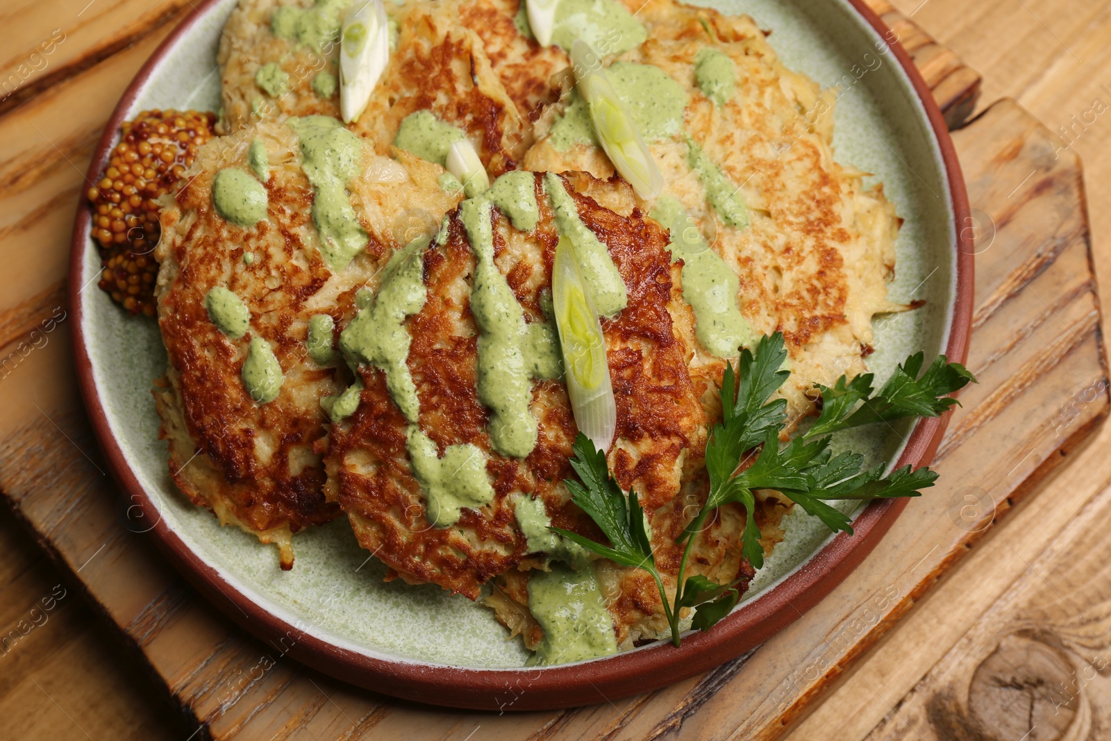 Photo of Tasty parsnip cutlets with sauce on wooden table, above view