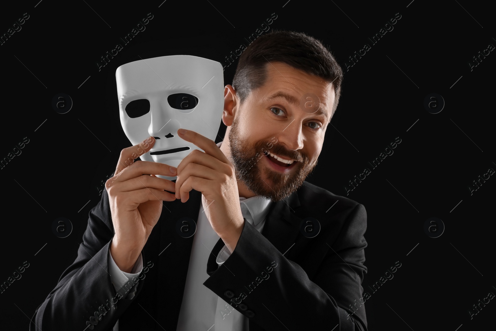 Photo of Multiple personality concept. Happy man with mask on black background