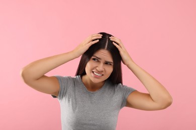 Photo of Emotional woman examining her hair and scalp on pink background
