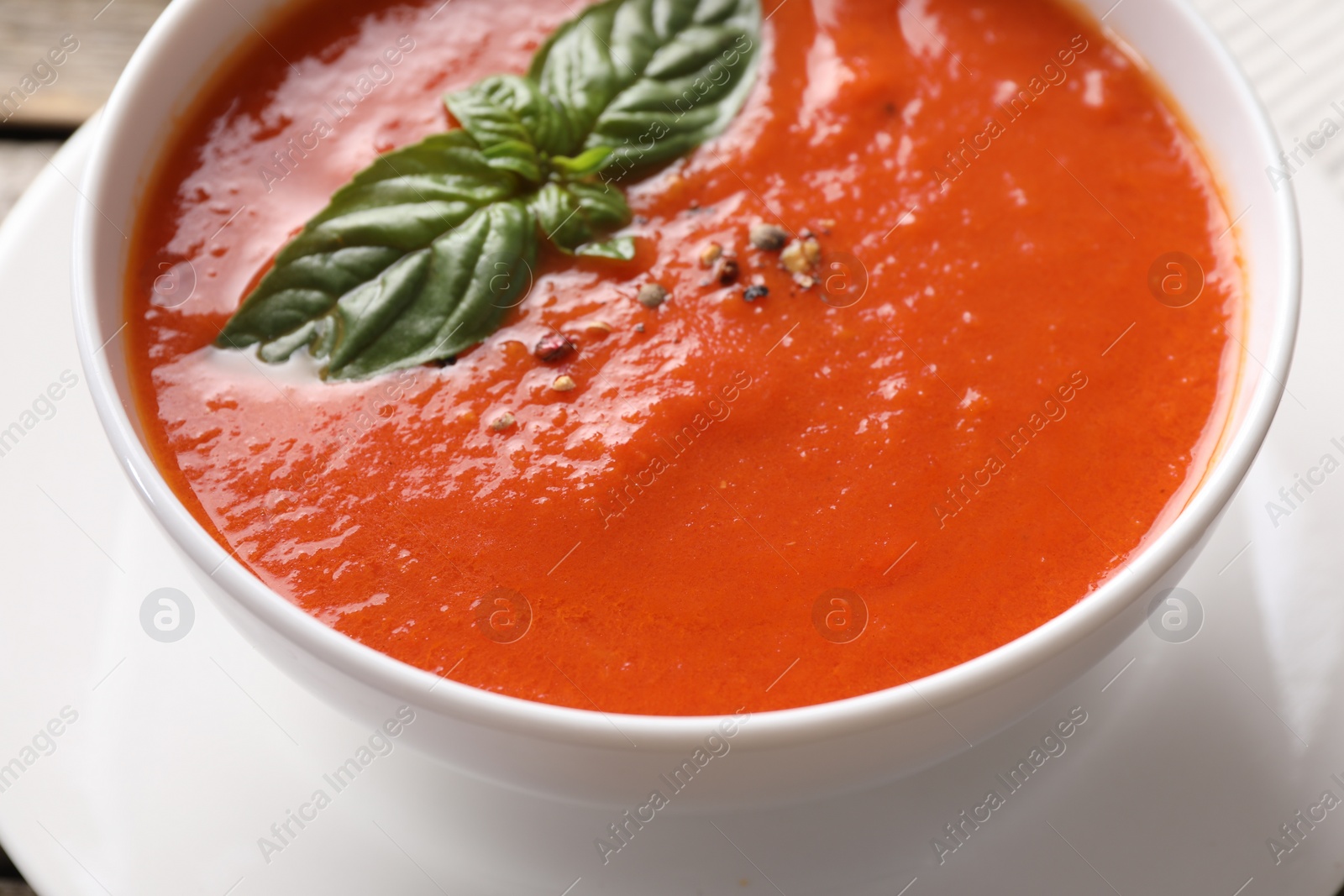 Photo of Delicious tomato soup with basil and spices on table, closeup