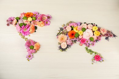 Photo of World map made of different beautiful flowers on light wooden table, flat lay