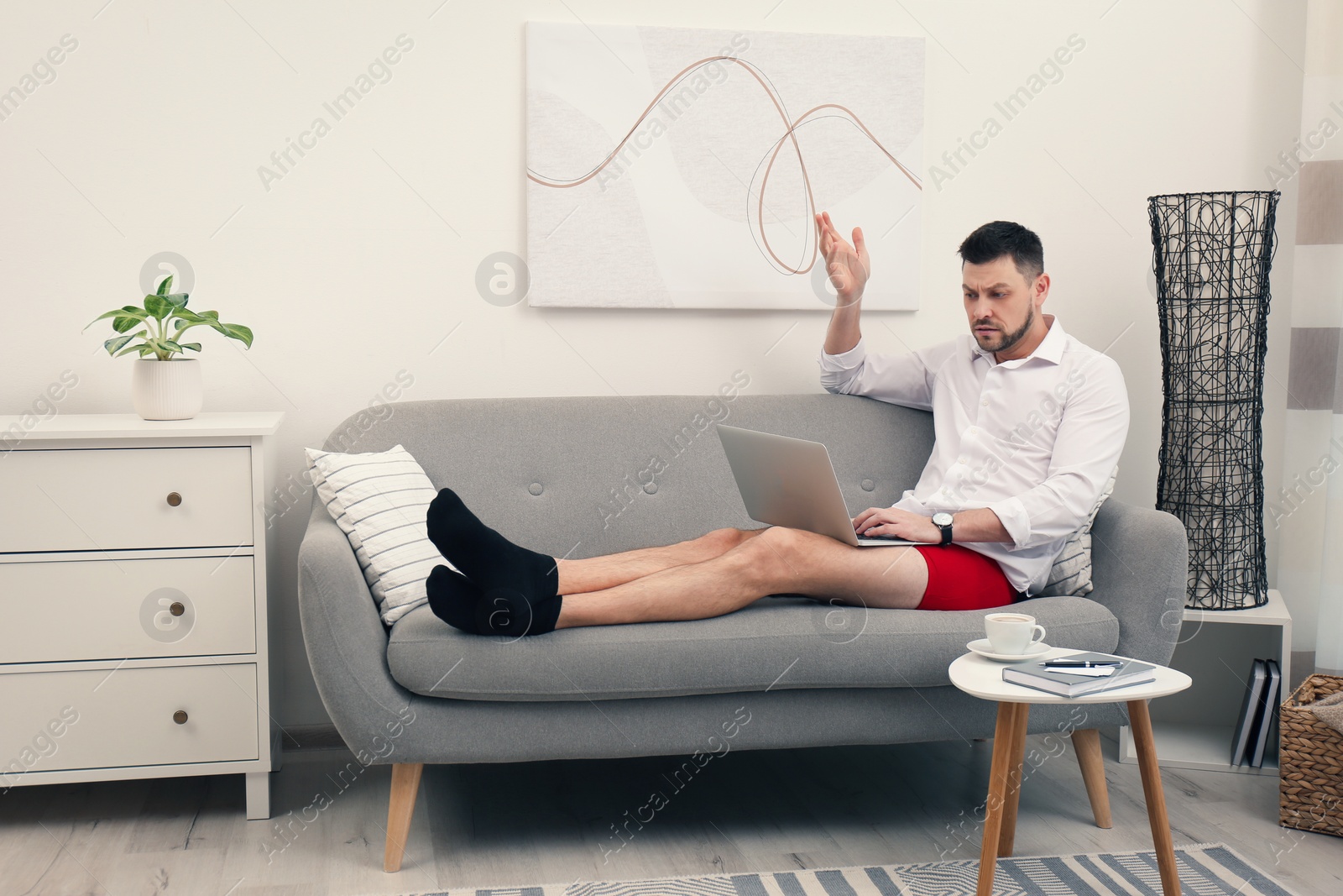 Photo of Businessman wearing shirt and underwear during video call at home