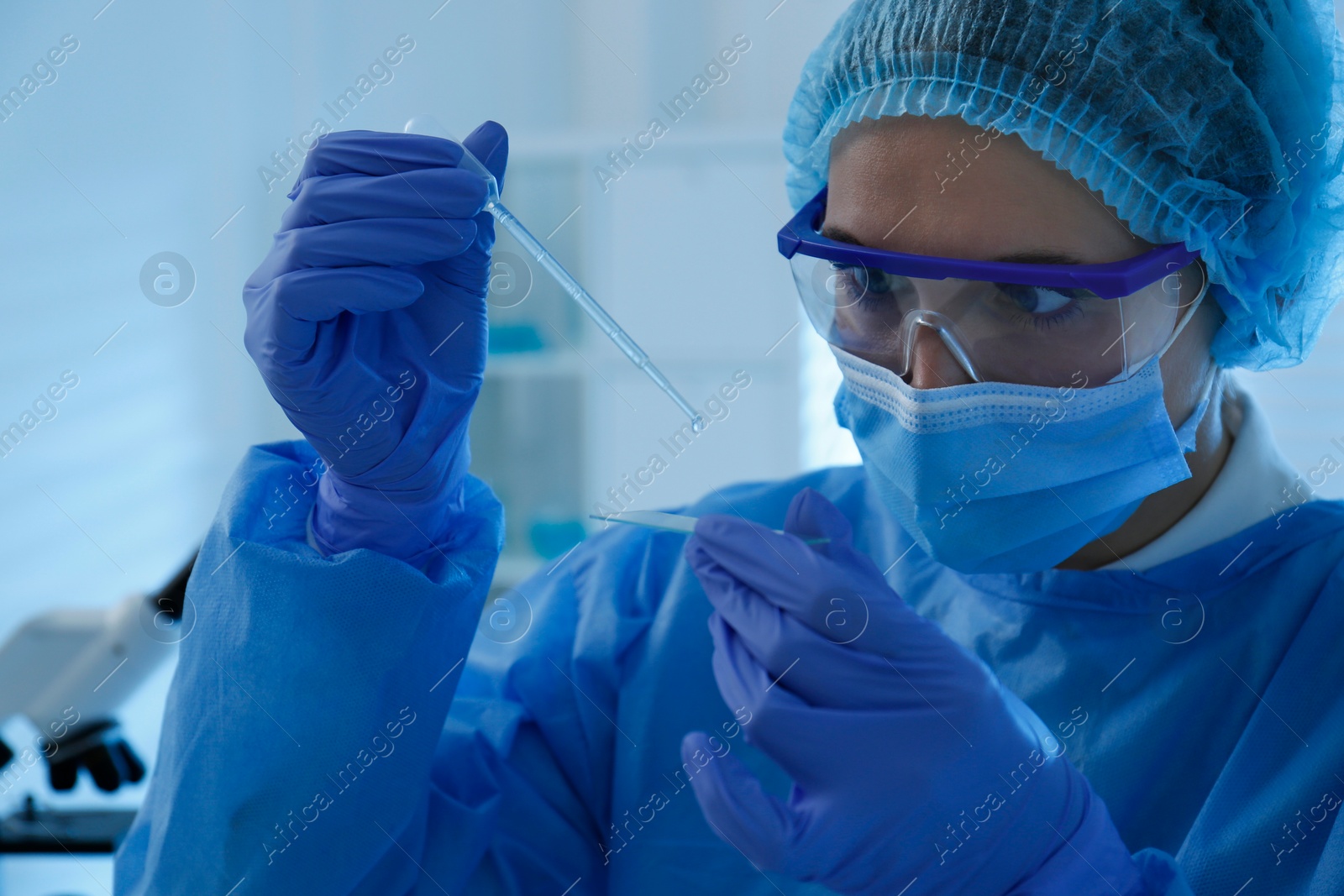 Photo of Scientist dripping sample onto glass slide in laboratory. Medical research