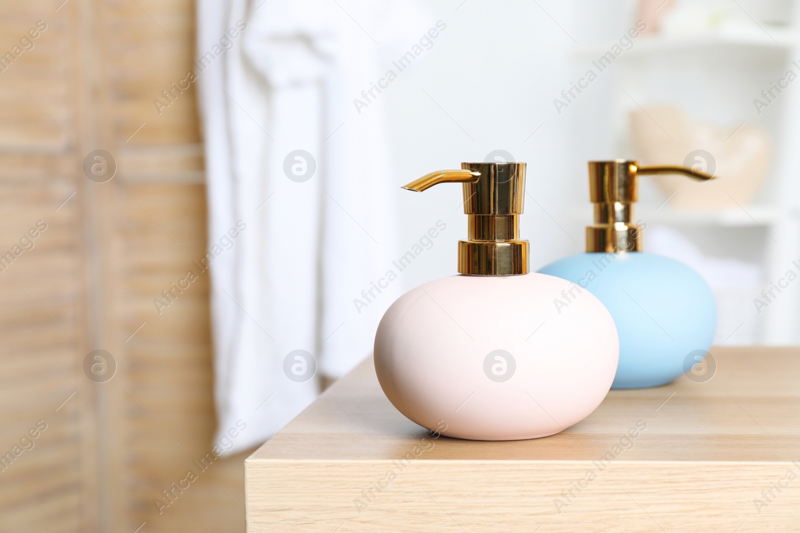 Photo of Stylish soap dispensers on table against blurred background. Space for text