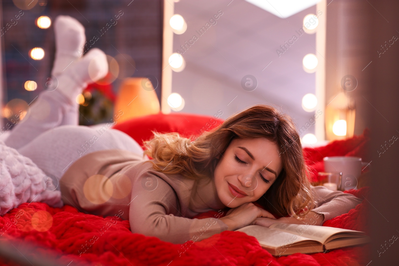 Photo of Beautiful young woman with book relaxing on bed at home. Cozy atmosphere